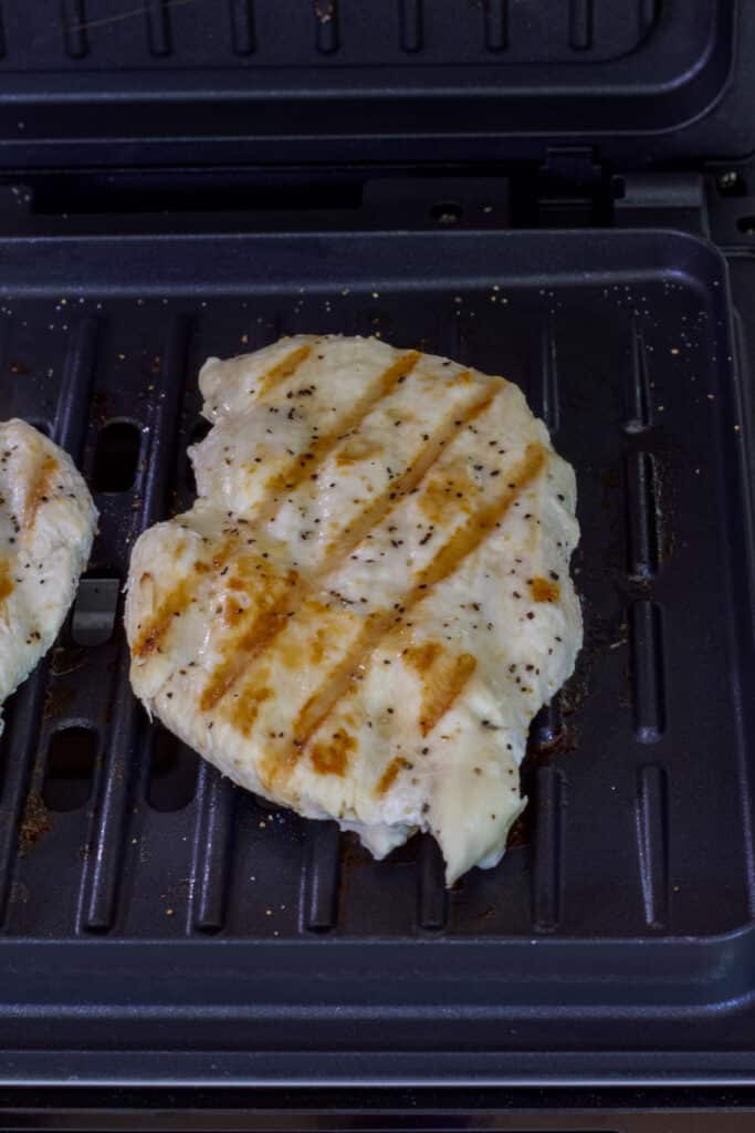 One cooked boneless skinless chicken breasts on a George Foreman grill.