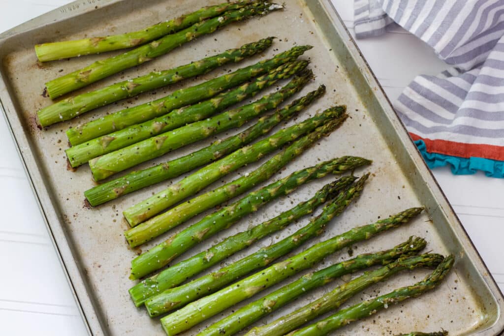 The delicious asparagus on a silver rimmed baking sheet after it came out of the oven.