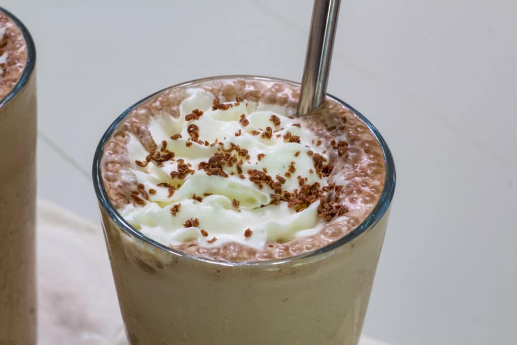 Overhead view of one glass of Starbucks Mocha Frappuccino Recipe (with instant coffee) so the whipped cream and chocolate shavings are visible.