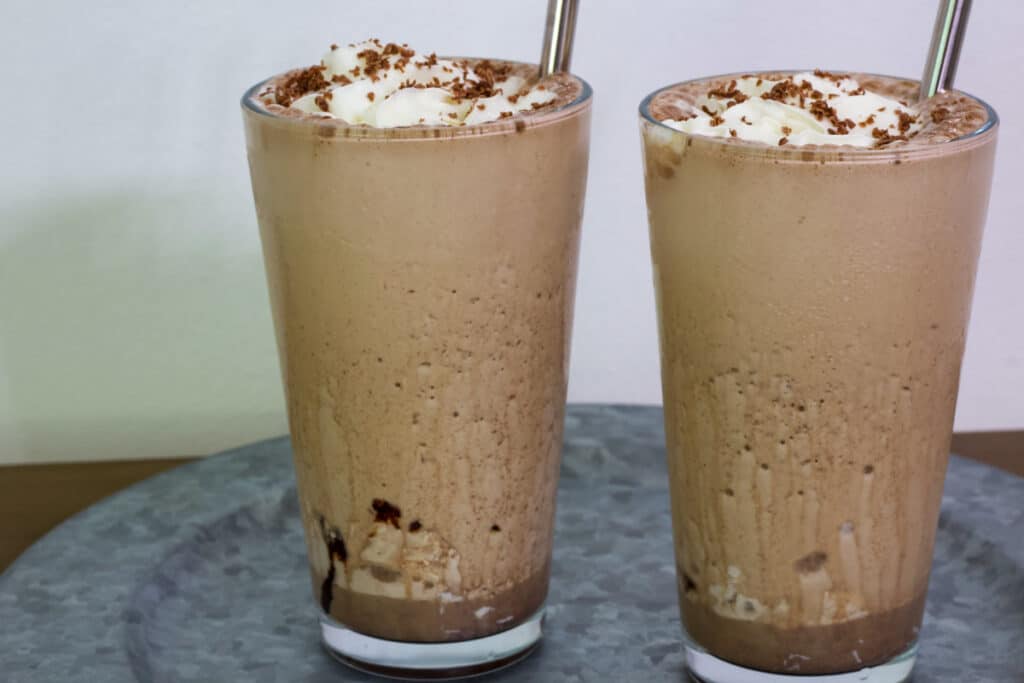 Side view of two glasses full of Starbucks Mocha Frappuccino that was made with instant coffee.