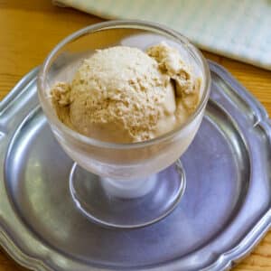 The feature image of one scoop of ice cream in a glass dish that is on a silver plate.